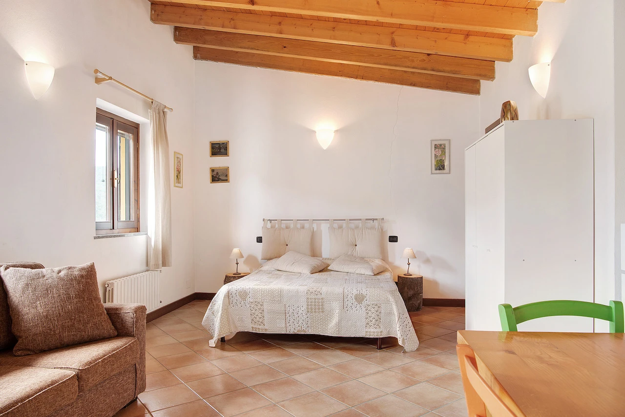 Letto matrimoniale del Classic Cottage XL visto dalla zona open space alla Tenuta MonteOliveto